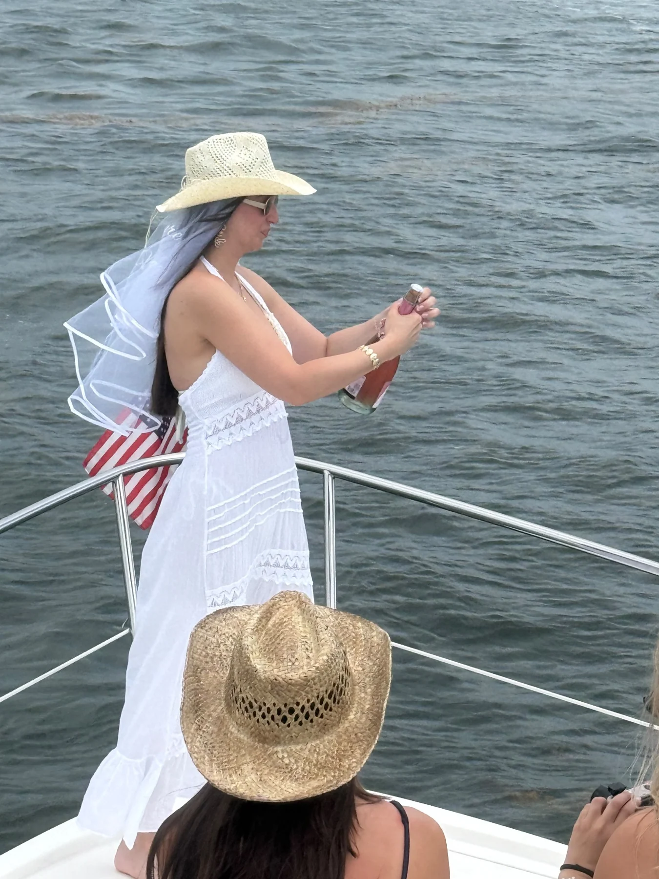 A guest in a veil and sun hat looking across the water from the bow