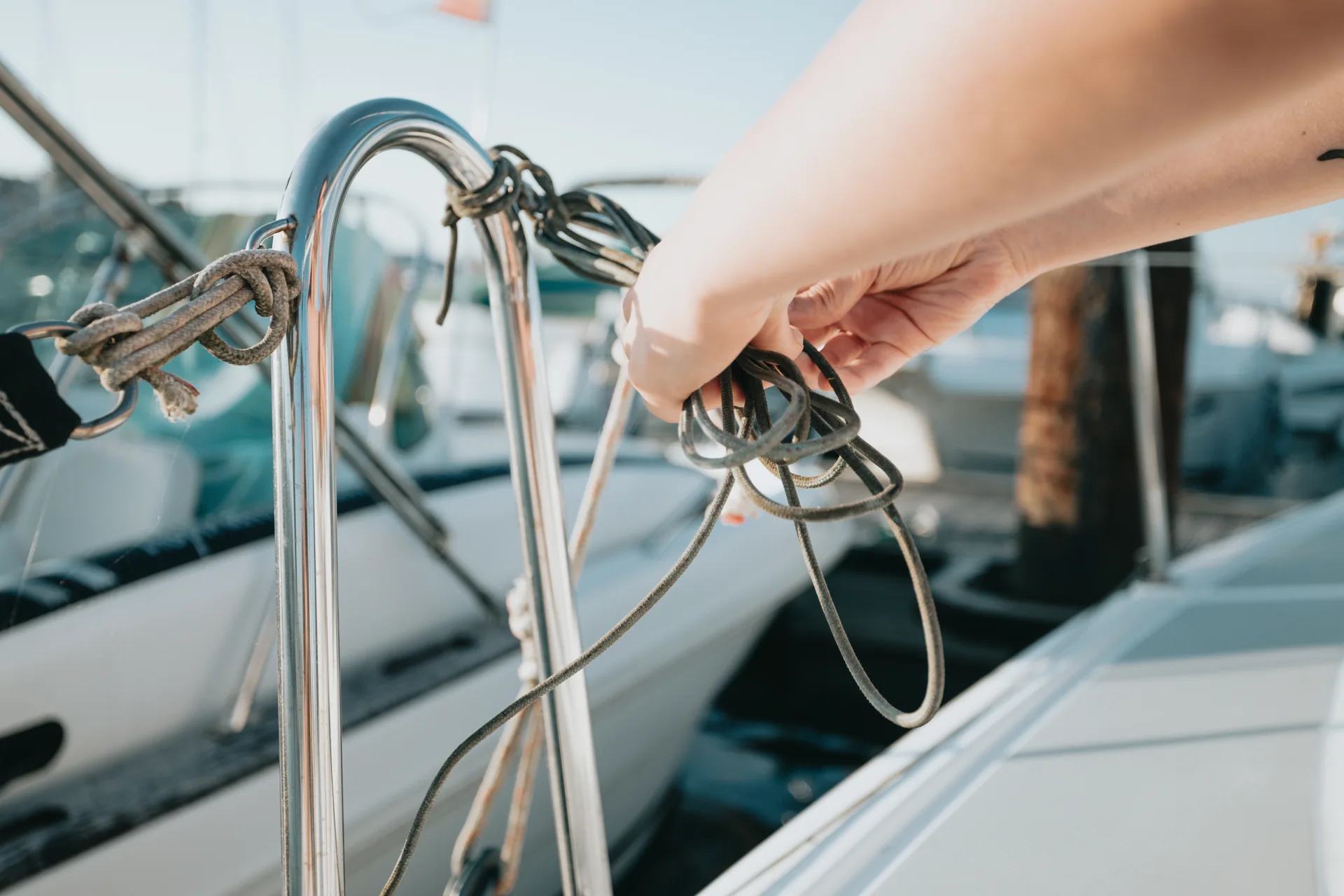 Hands carefully securing a nautical line at a yacht railing